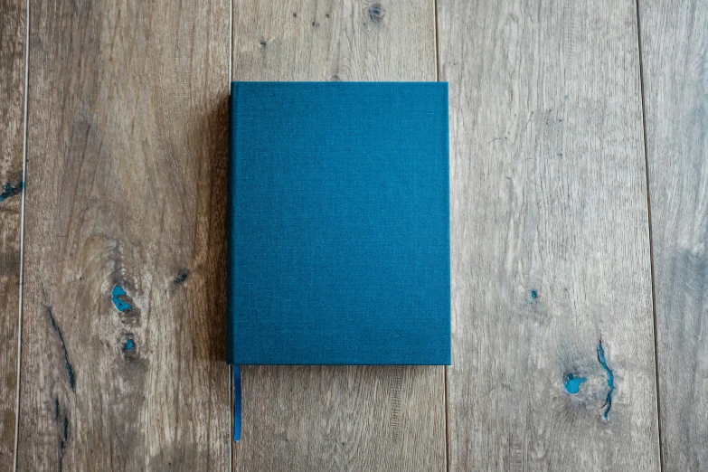 a blue book is laying on a wooden floor