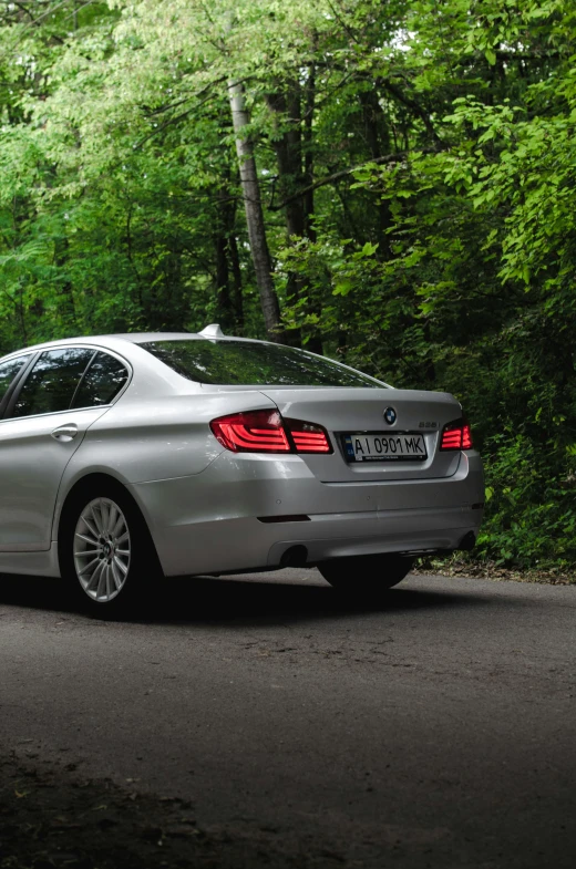 a silver car parked on the side of a road in front of green trees