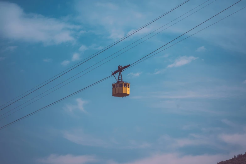 an aerial lift with a man riding the lift, and the sky in the background