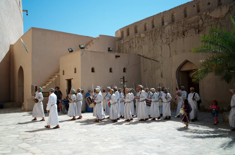 several men in white walking toward an old building