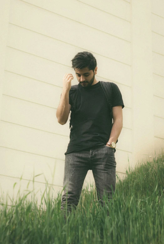 a man standing in the grass wearing a black shirt
