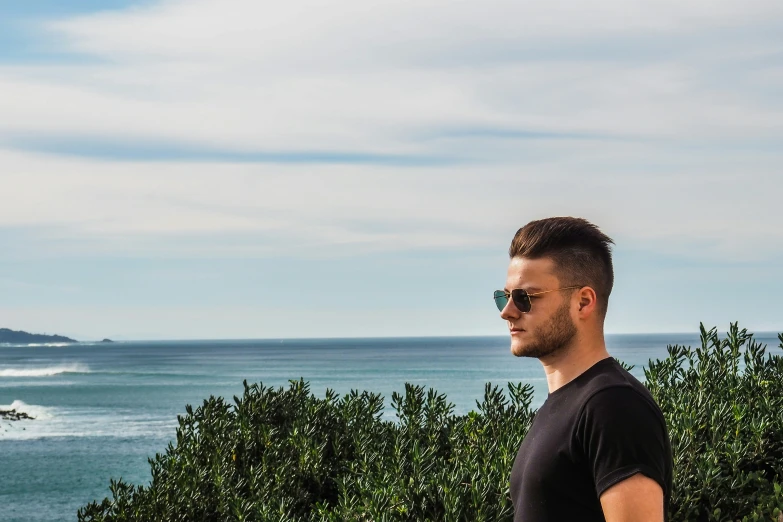 a man standing with an ocean in the background