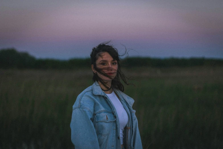 a girl is standing outside at dusk