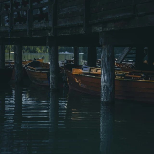 some boats that are in some water next to some wooden poles