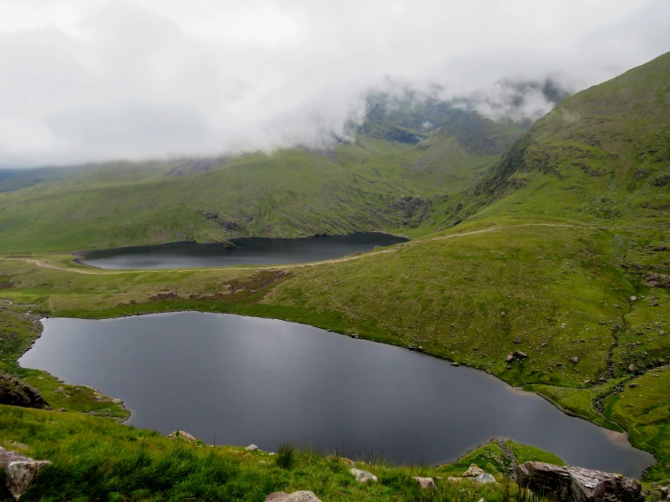 water is seen in a mountain lake surrounded by grass