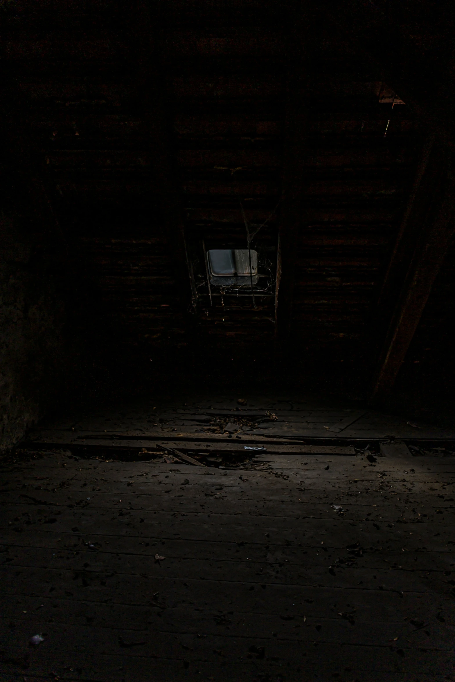 an empty dimly lit room with exposed wood floors