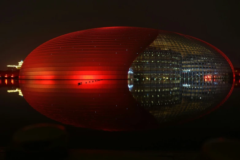 the building is lit up and reflecting it's lights in water