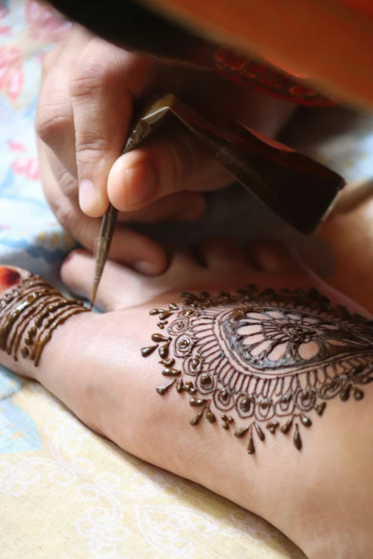 a woman has her foot painted with henna