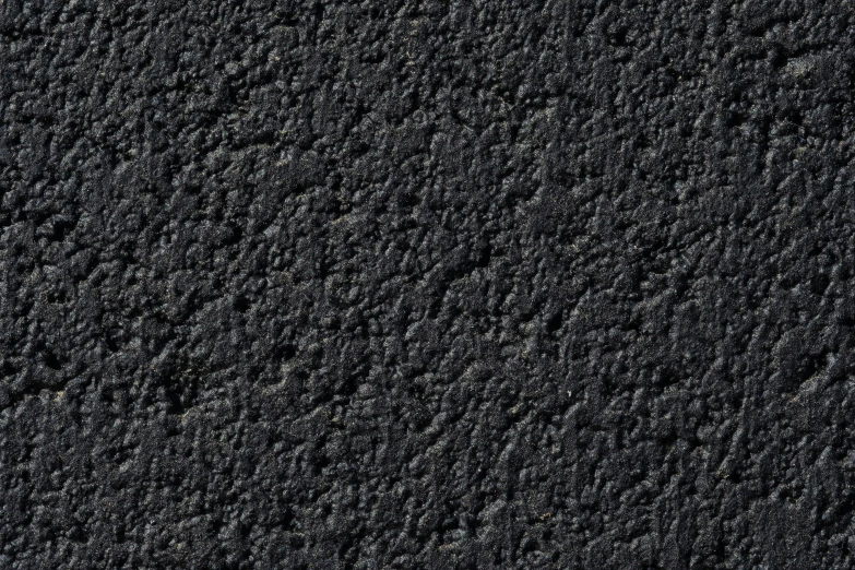 some grey asphalt with black dots near some rocks