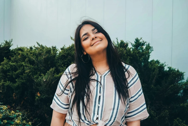 a women who is smiling standing next to some trees