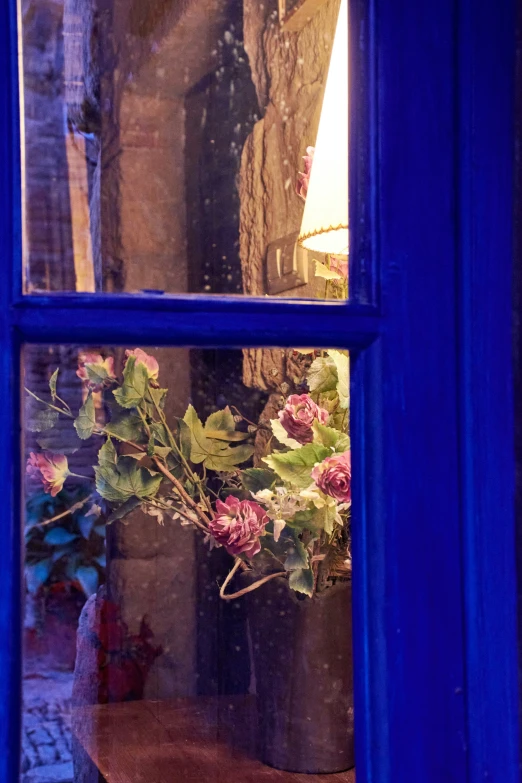 the vase is on a wooden shelf behind an open window