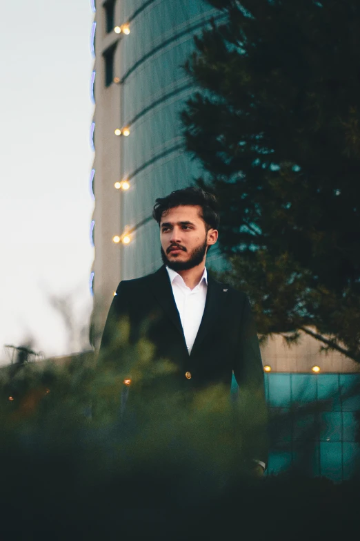 a man standing in front of a tall building with trees