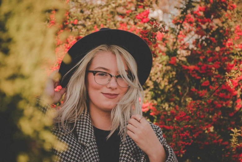 a woman with glasses wearing a black hat