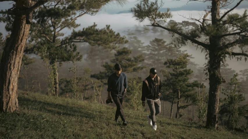 two men walk up a hill surrounded by trees