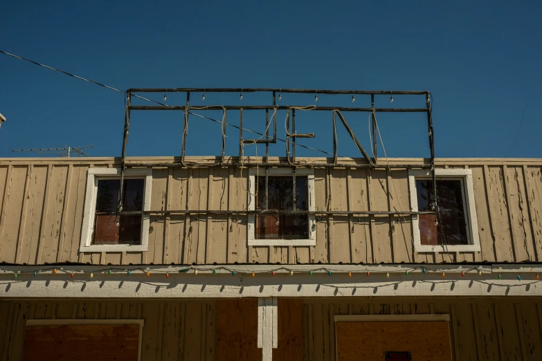 a sign hangs from the roof of a building with two windows