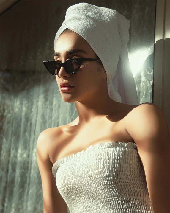 a woman in sunglasses and a towel on her head