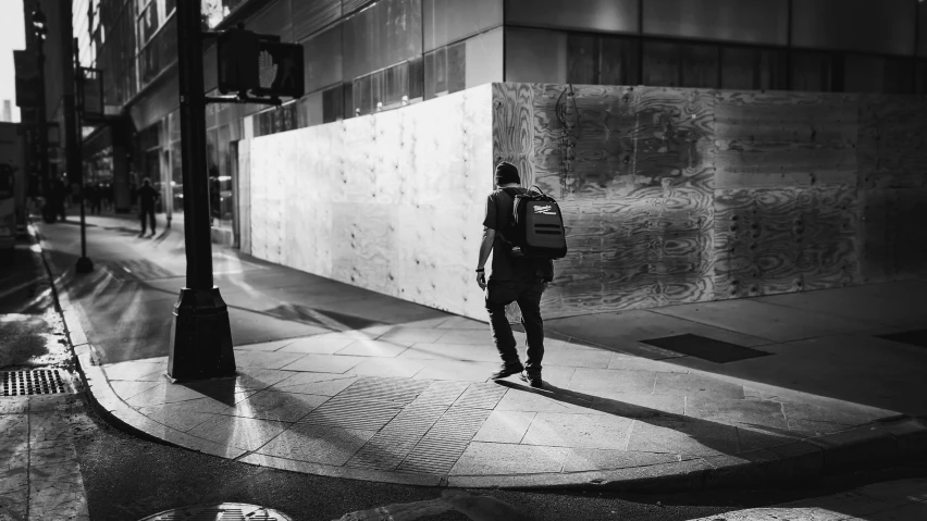 a young man walking down a street past a tall building