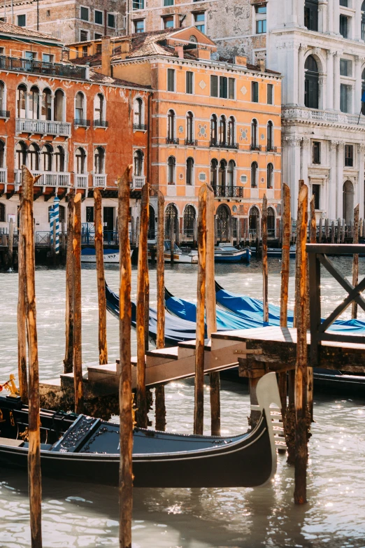 the gondolas are docked next to the wooden poles in a body of water