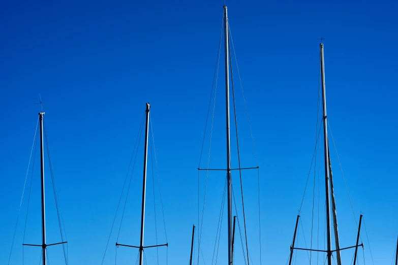 several masts of boats in the sea on a sunny day