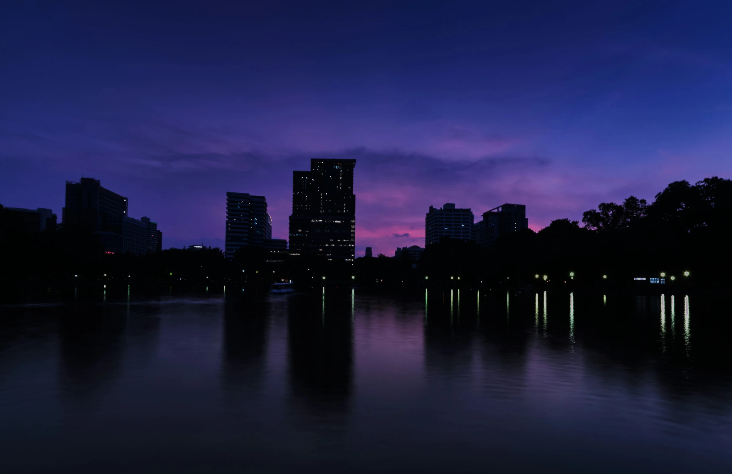 a city with lights that are on is sitting next to the water