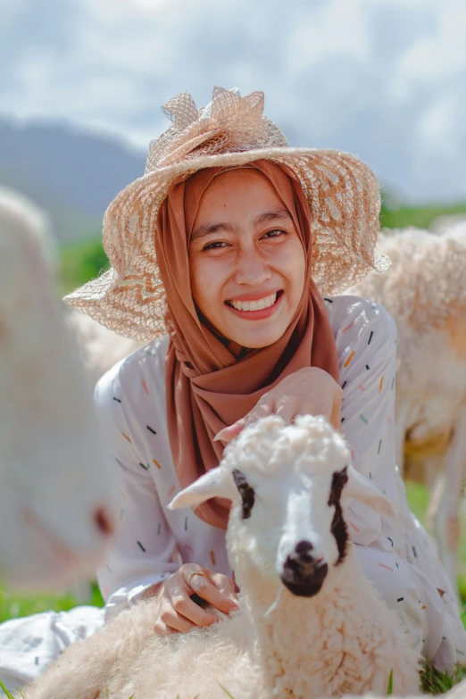 a lady with a hat on posing for a po with a sheep