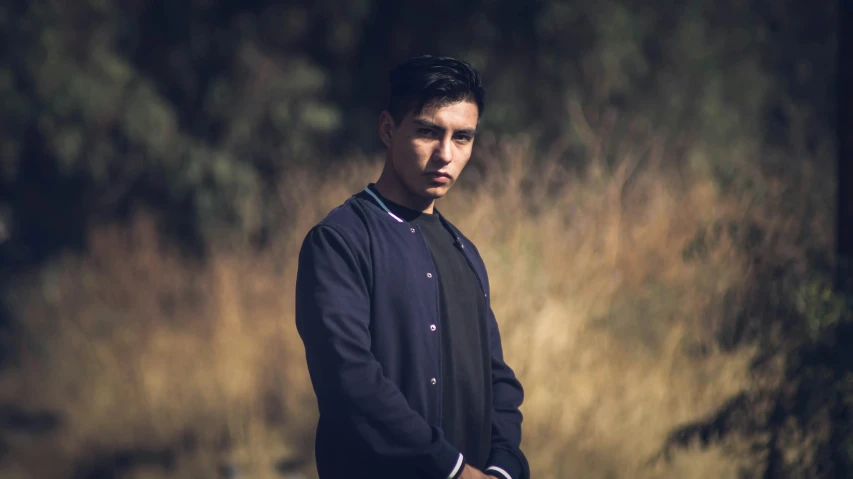 a young man standing outside on a grassy field