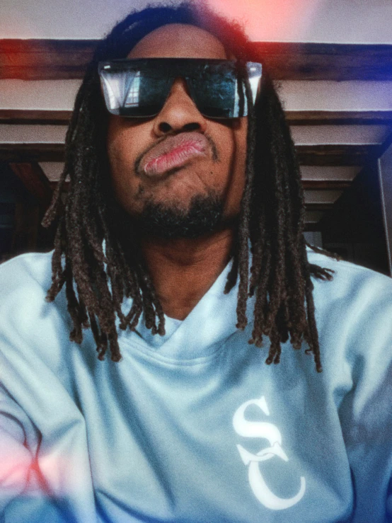 a young man with sunglasses and dreads wearing a t - shirt