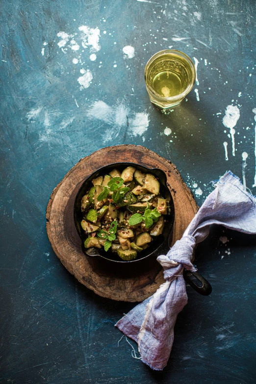 a pot filled with vegetables next to a glass of wine