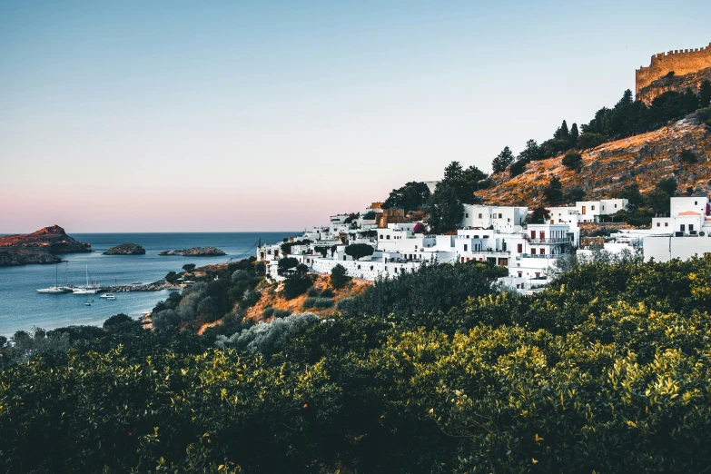 a small village on top of a hill next to the water