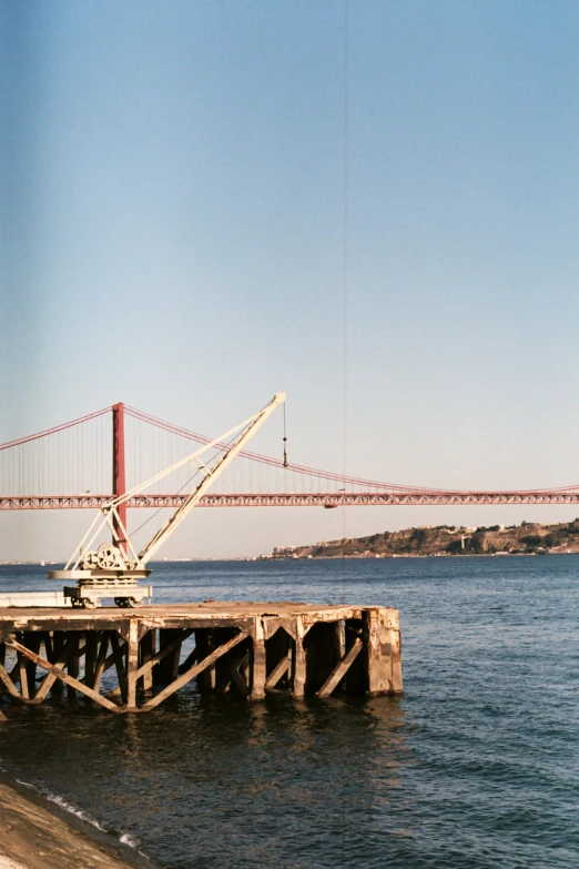 the boat is tied up near a large bridge