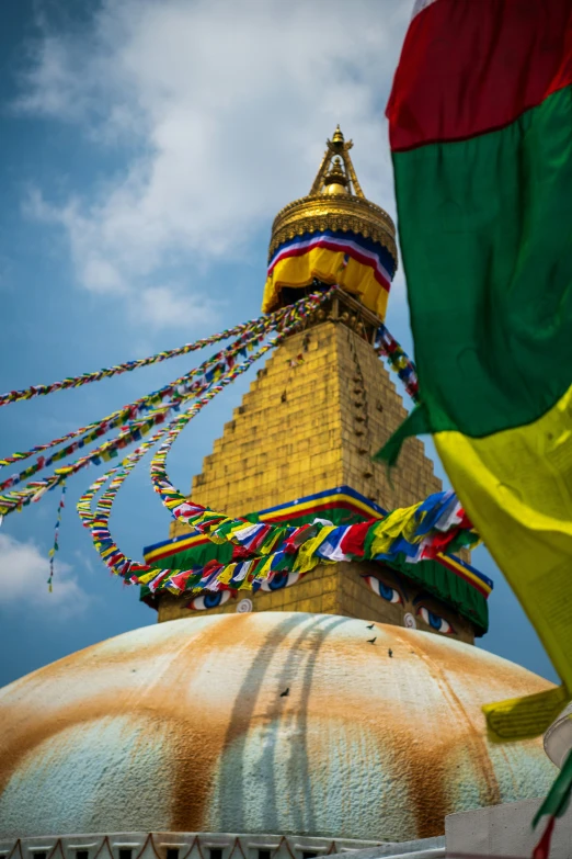 a tall yellow tower with multiple flags around it