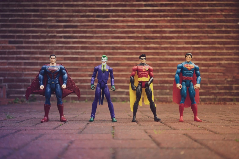 five action figures lined up near a brick wall