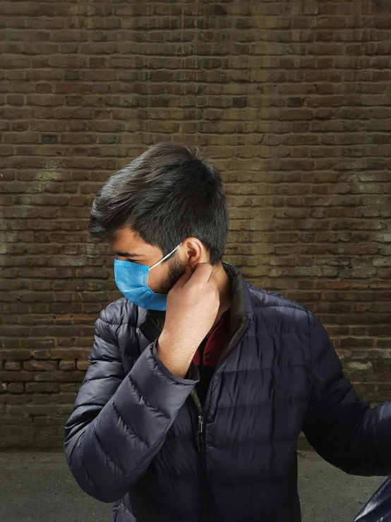 the man wearing a mask has his hand on his cheek