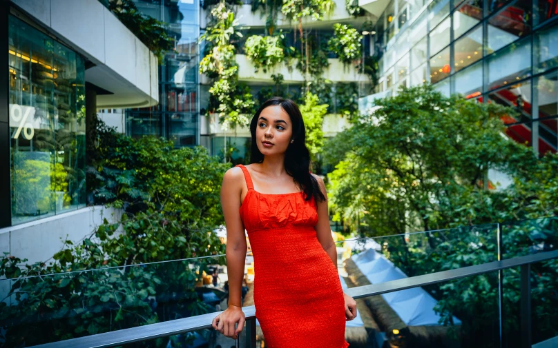 a woman in a red dress standing near an outside wall