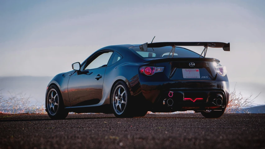 the rear end of a sports car that is parked on a road