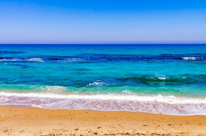 the wave hitting on the beach in front of blue ocean