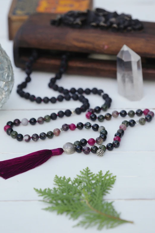 a cross is surrounded by beads and a crystal on the table