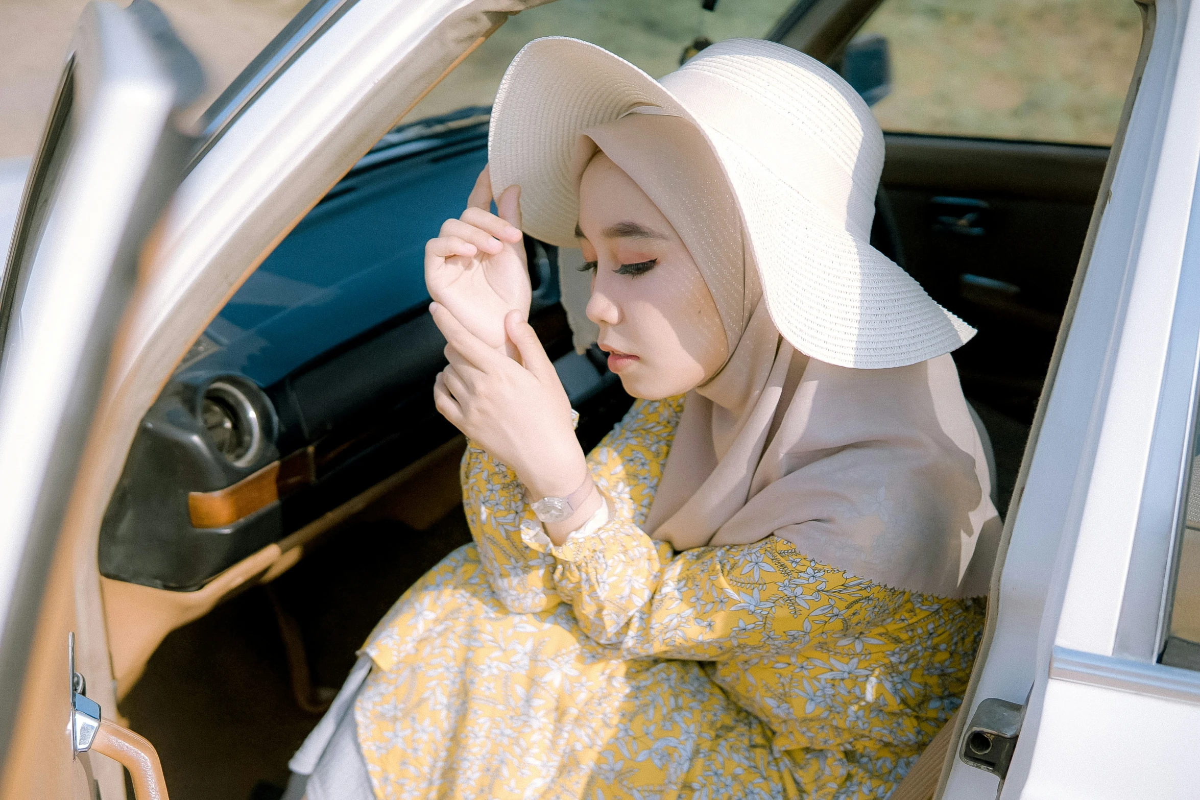 a woman in a yellow and gray dress is leaning out of a car