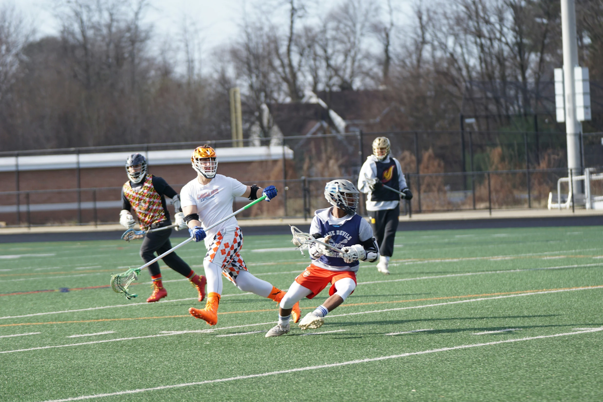 three s running on the field during a lacrosse game