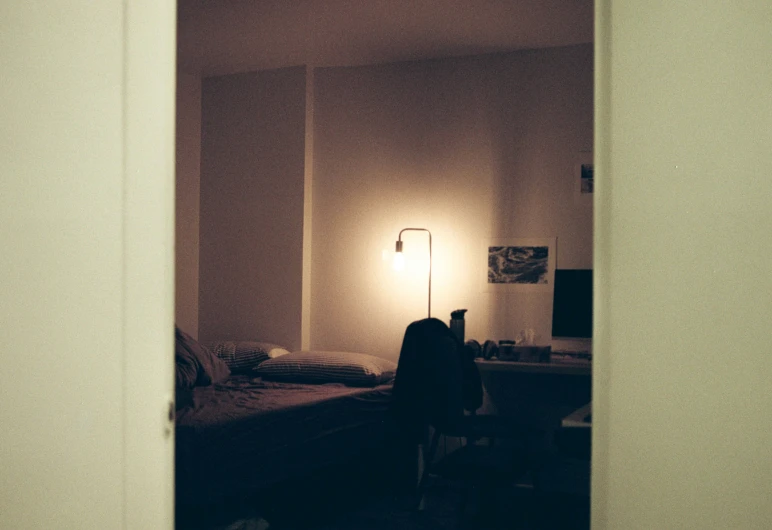 a bed with a dark color and a lamp with an orange bulb