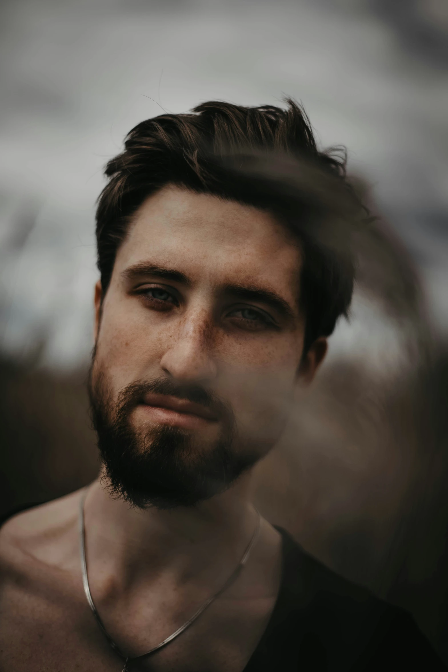 a man with beard and necklace looking at the camera