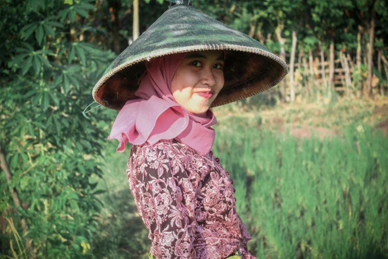 a young woman with a hat that is standing in a field