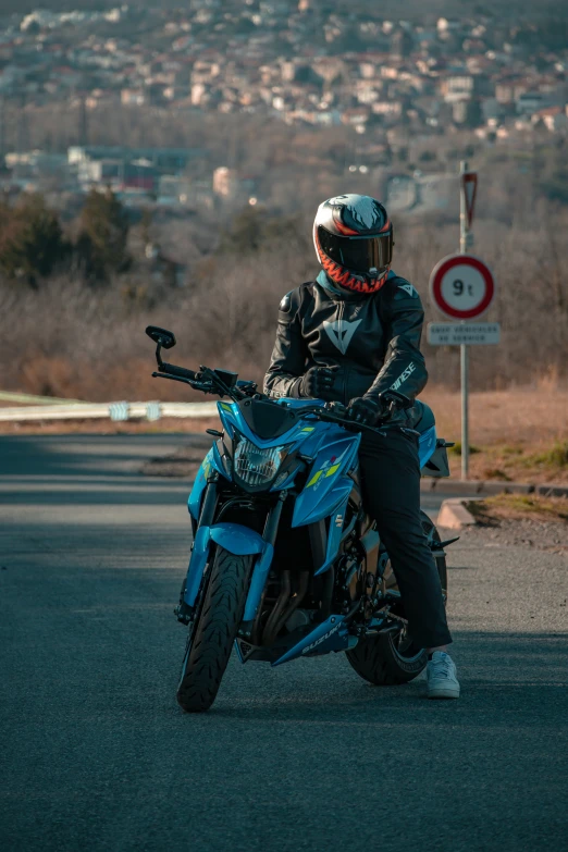 a man on a blue motorcycle is in the road