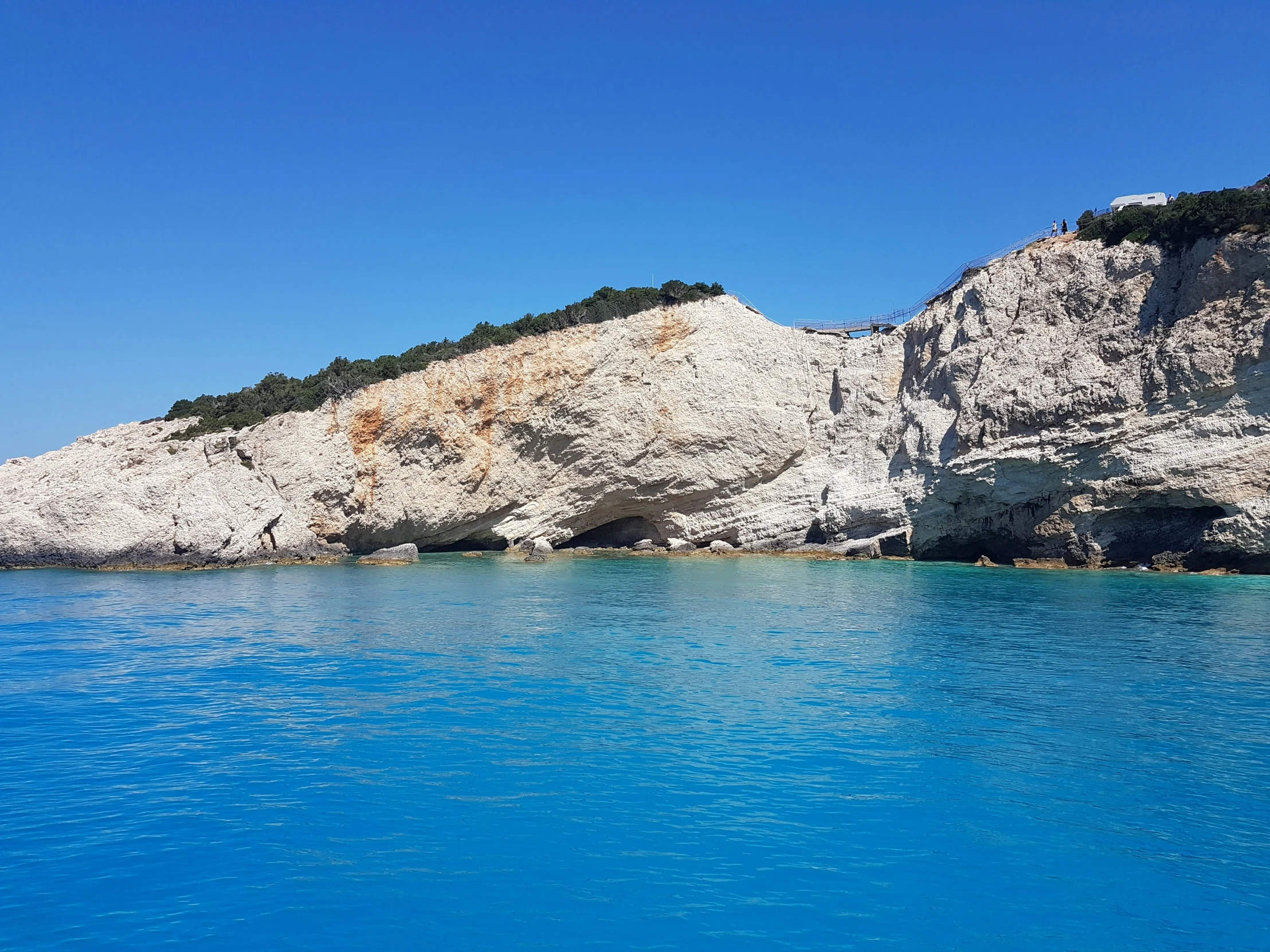 the side of a cliff overlooking water that has blue water and no snow