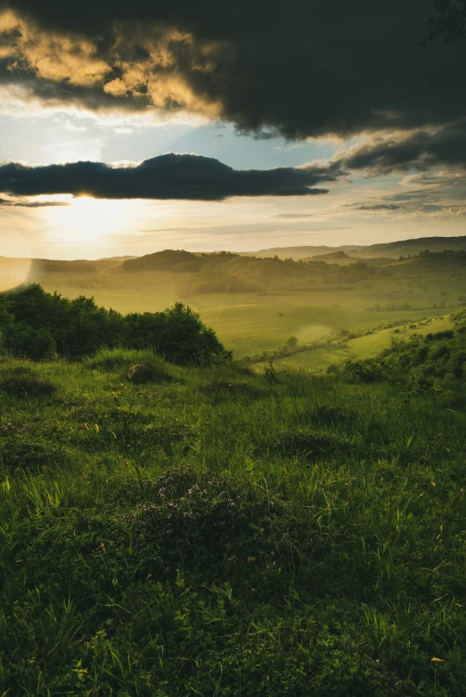 the sun sets in a scenic scene of rolling hills