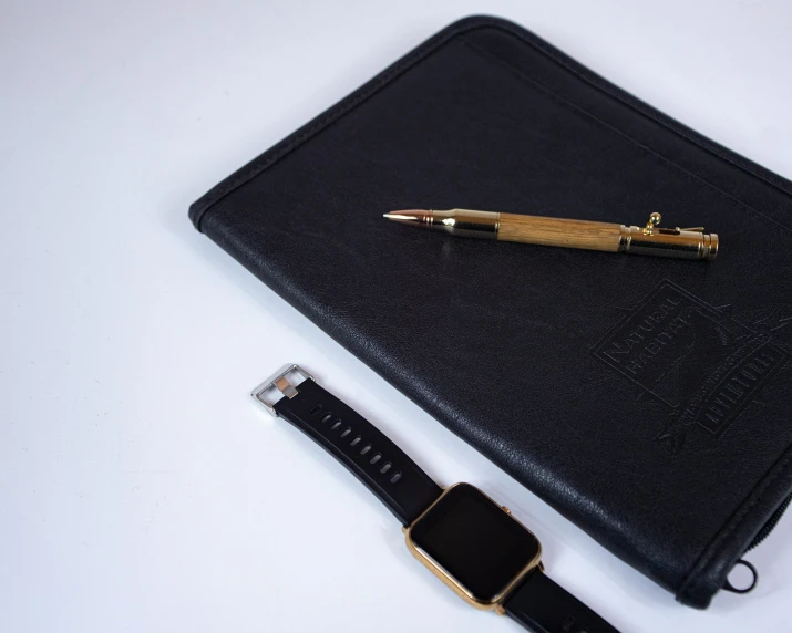 pen laying on top of a case near a black watch