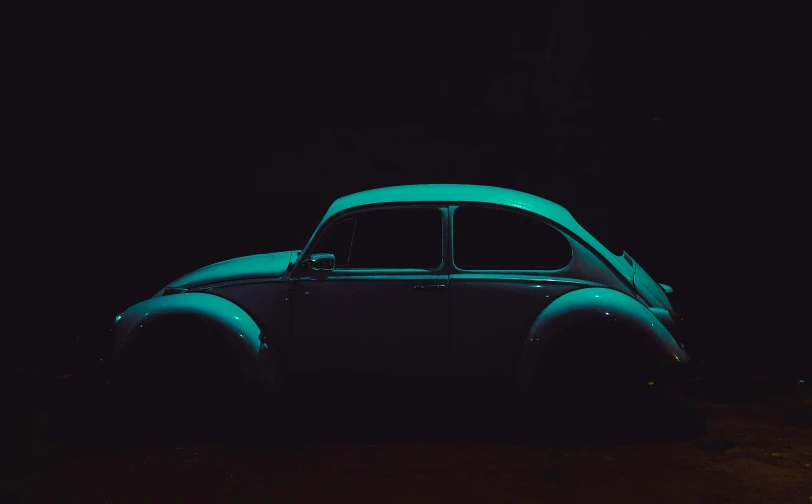 an old car sitting on the dark pavement