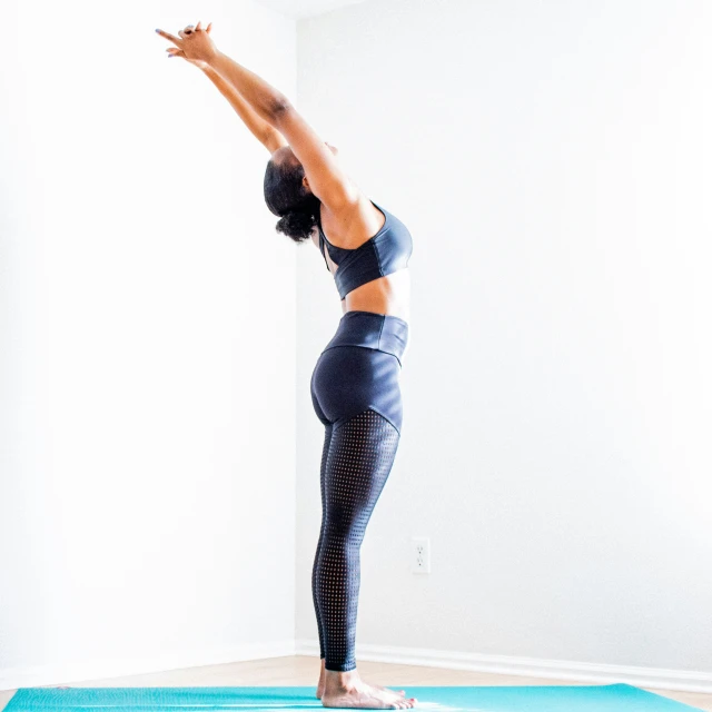 a woman stands on a yoga mat with one leg up while performing a standing pose