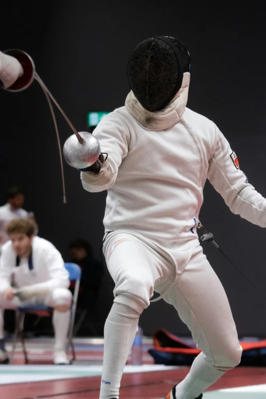 a person in fencing gear is jumping while others watch