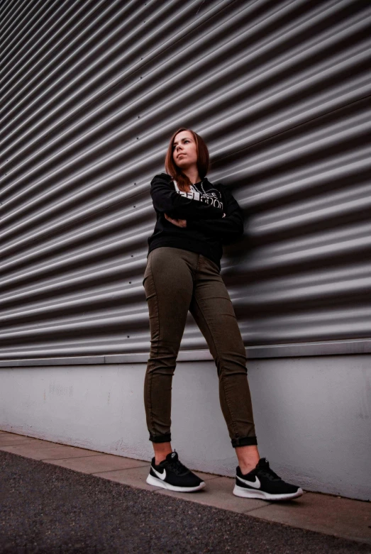 a beautiful woman standing against a wall near a building